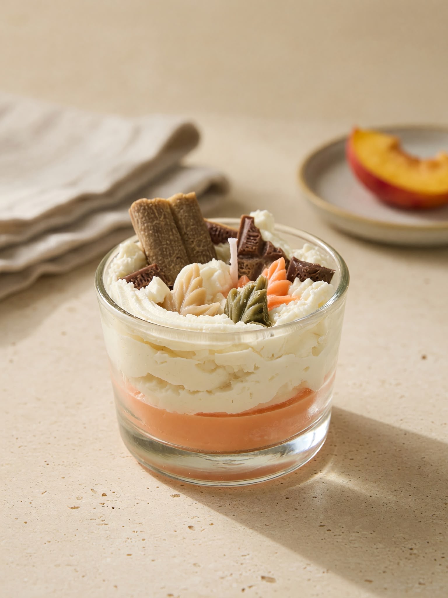 Layered orange and ivory candle in a glass with decorative toppings
