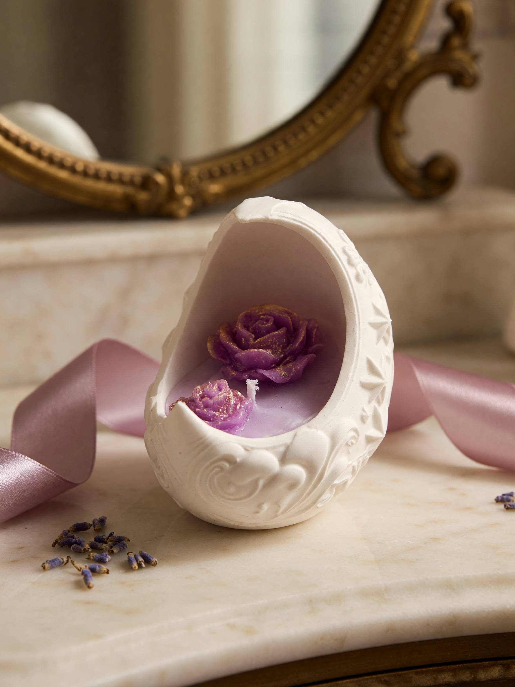 Ornate open ivory vessel containing a purple candle with floral details