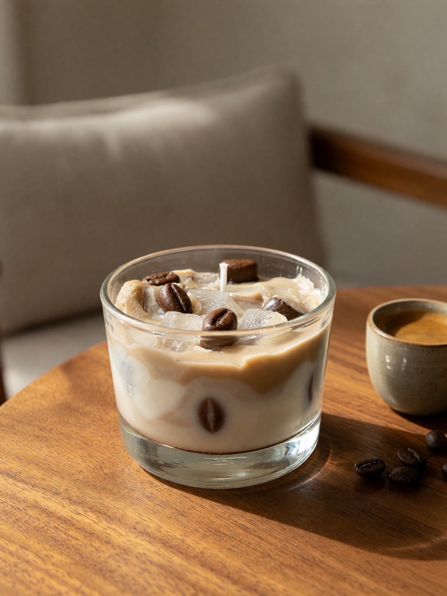 Cream and brown candle in a glass with coffee-bean and ice-shaped decorations