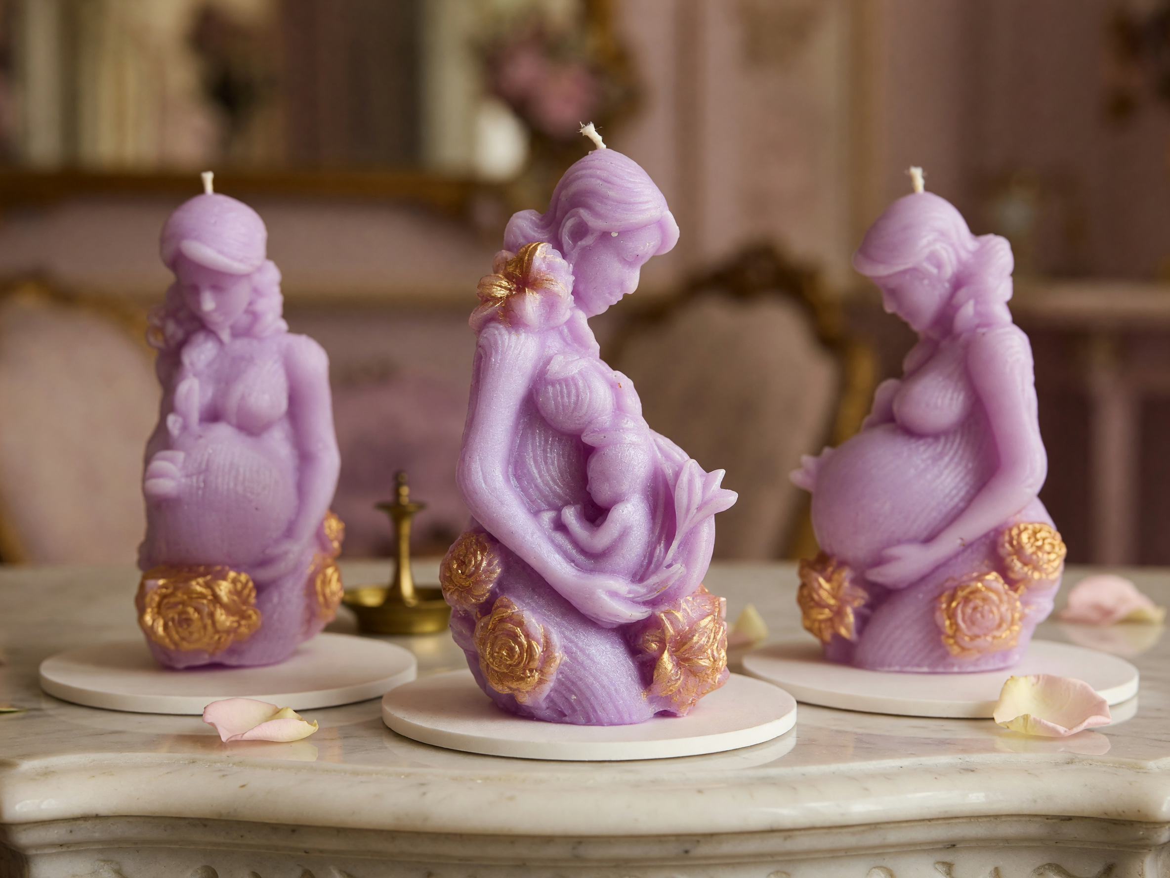 Three purple sculptural mother and baby candles with golden floral accents