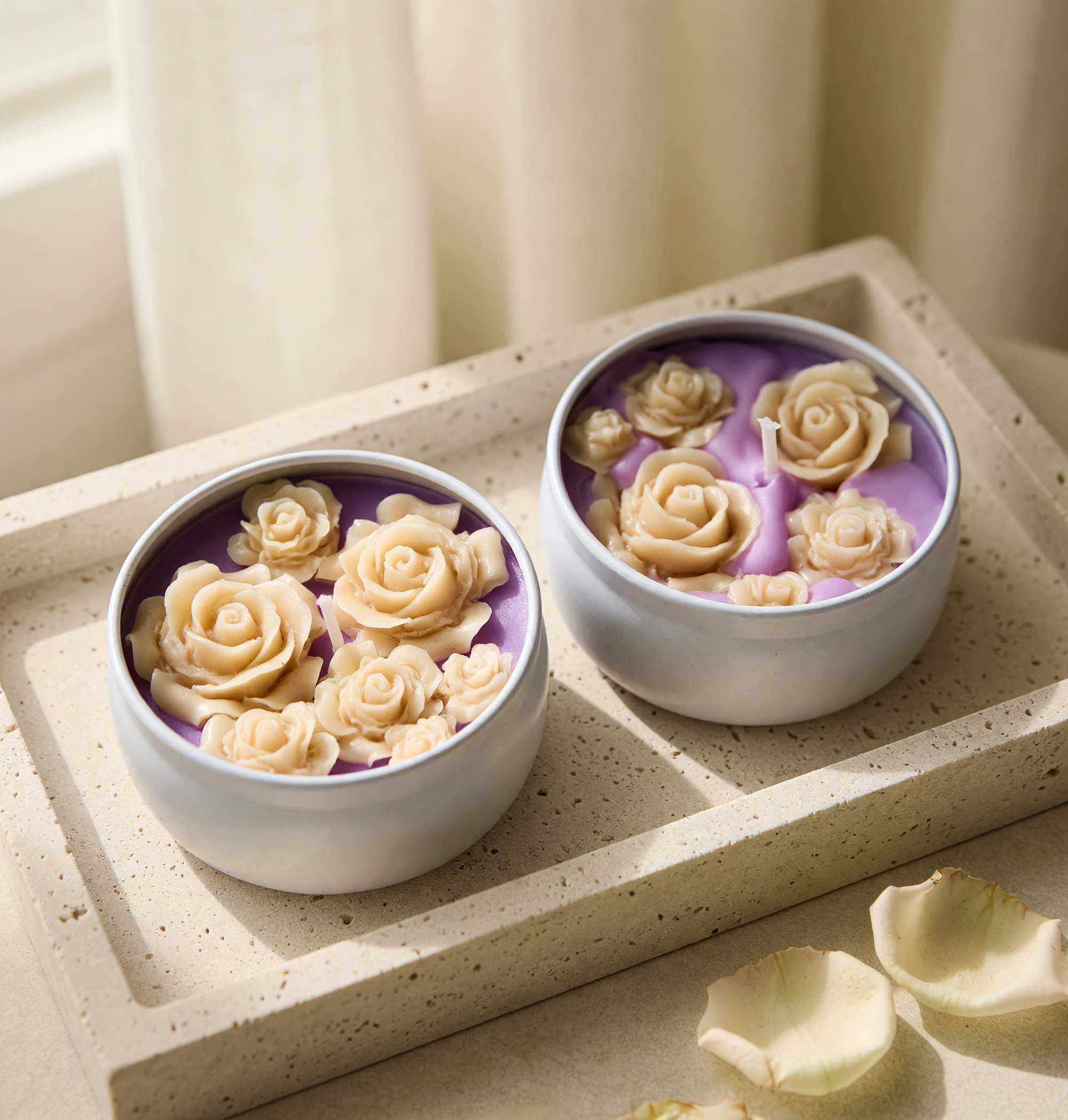 Two silver candle tins with purple wax and cream-colored wax roses