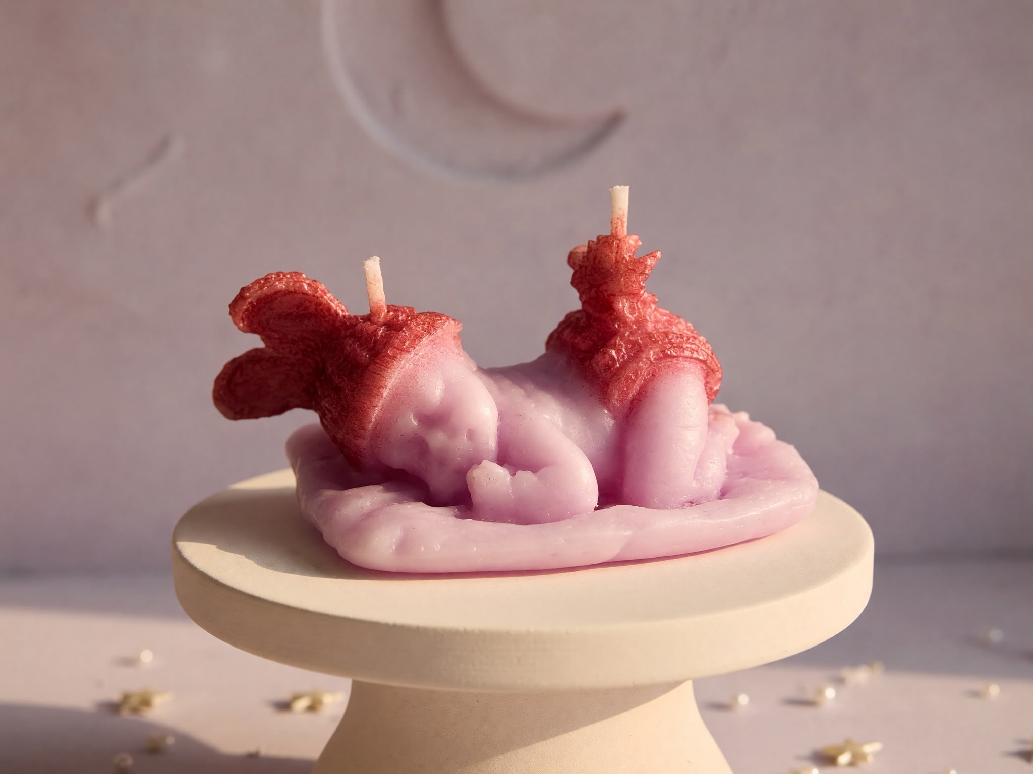 Pink sleeping baby candle with a bow and two visible wicks